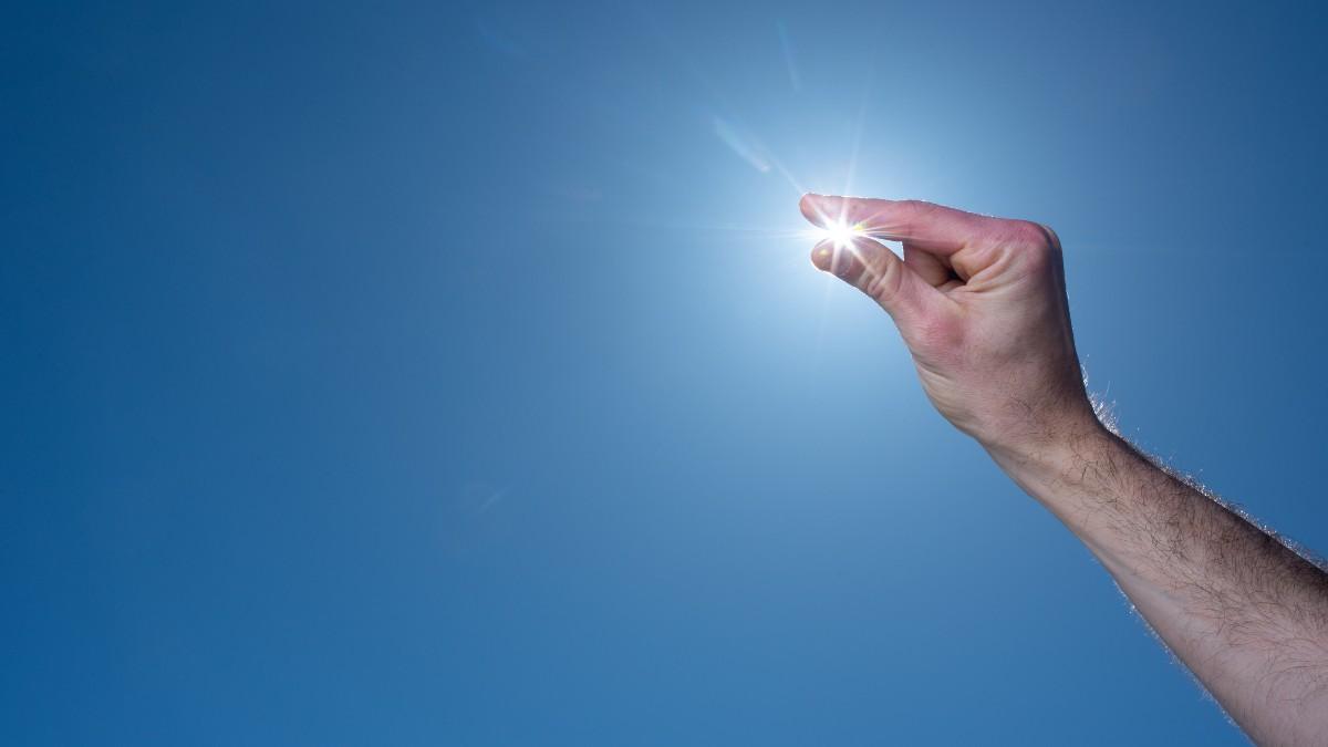 在万里无云的蓝天上，一个人斜视着太阳的手指. 