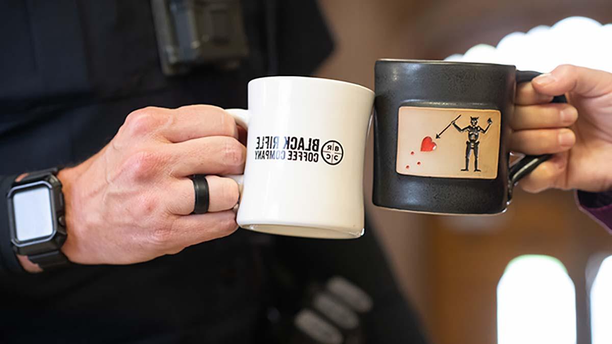 两名老兵拿着印有黑步枪咖啡公司标志的咖啡杯.